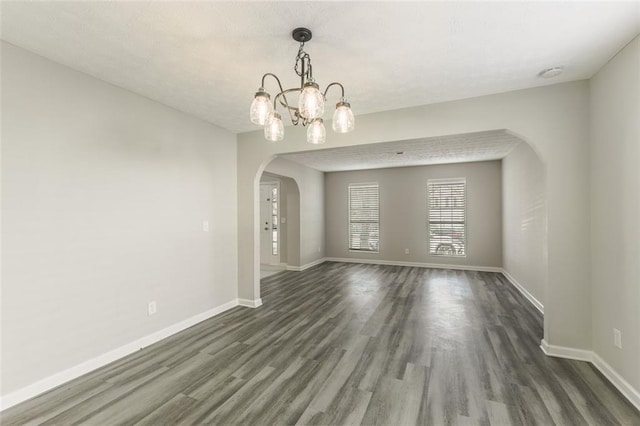 spare room with dark hardwood / wood-style floors and a chandelier