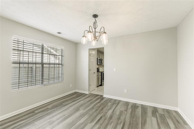 empty room featuring an inviting chandelier and light hardwood / wood-style floors