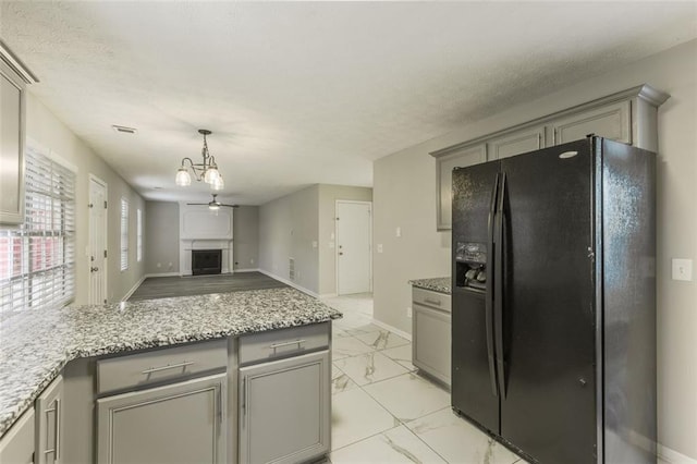 kitchen featuring pendant lighting, gray cabinets, an inviting chandelier, light stone counters, and black refrigerator with ice dispenser