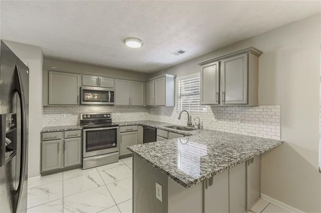 kitchen with sink, dark stone countertops, gray cabinetry, black appliances, and kitchen peninsula