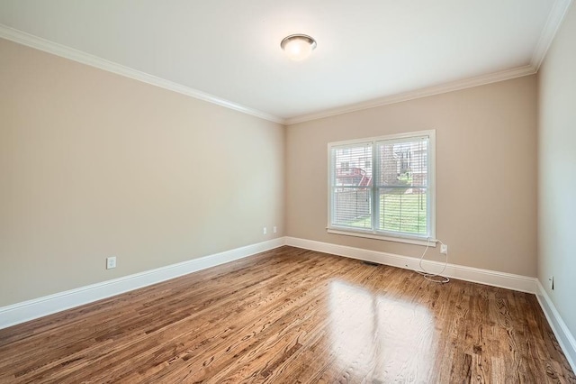 unfurnished room with crown molding, baseboards, and wood finished floors