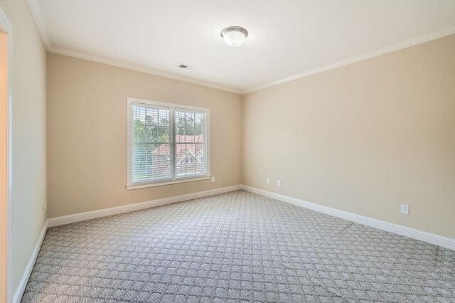empty room with carpet flooring, crown molding, visible vents, and baseboards
