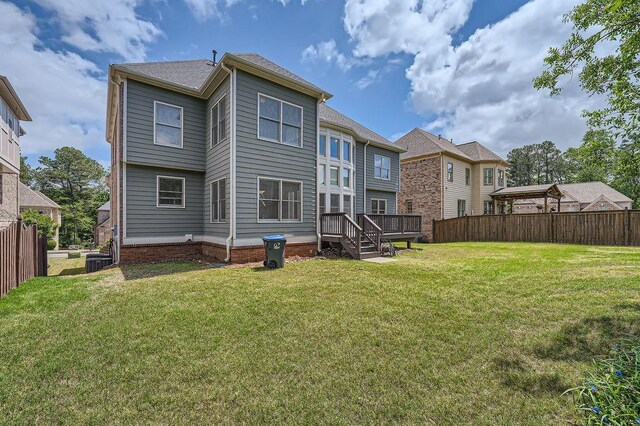 rear view of property featuring fence, central air condition unit, and a lawn