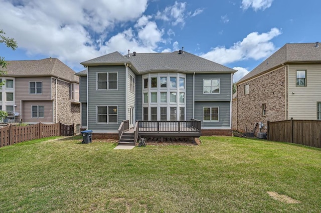 rear view of property featuring a lawn, fence, and a deck