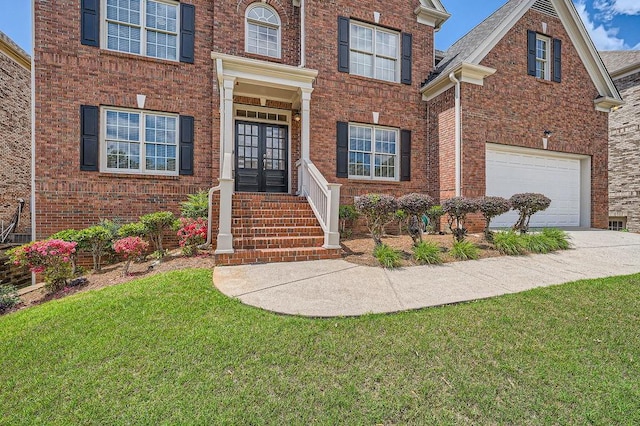 view of front of property featuring a front yard, french doors, brick siding, an attached garage, and driveway
