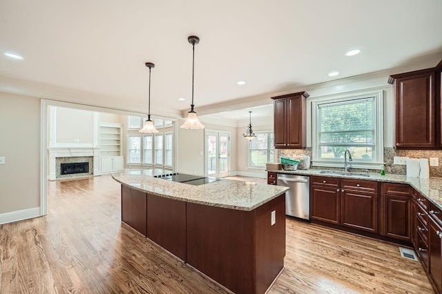 kitchen featuring a sink, light wood finished floors, a fireplace, stainless steel dishwasher, and a kitchen island
