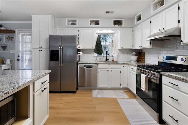 kitchen with visible vents, under cabinet range hood, light stone counters, a sink, and appliances with stainless steel finishes