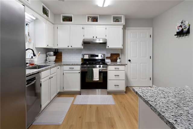 kitchen with under cabinet range hood, white cabinets, appliances with stainless steel finishes, and a sink