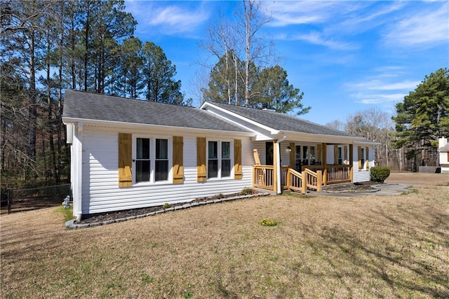 view of front of property featuring covered porch, a shingled roof, a front yard, and fence