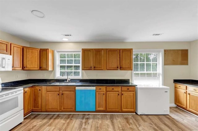 1141 Planing Mill Rd, Greensboro, GA 30642 - kitchen featuring white appliances, a sink, light wood-style flooring, brown cabinets, and dark countertops