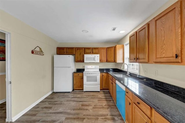 1141 Planing Mill Rd, Greensboro, GA 30642 - kitchen featuring white appliances, a sink, wood finished floors, brown cabinetry, and dark stone countertops