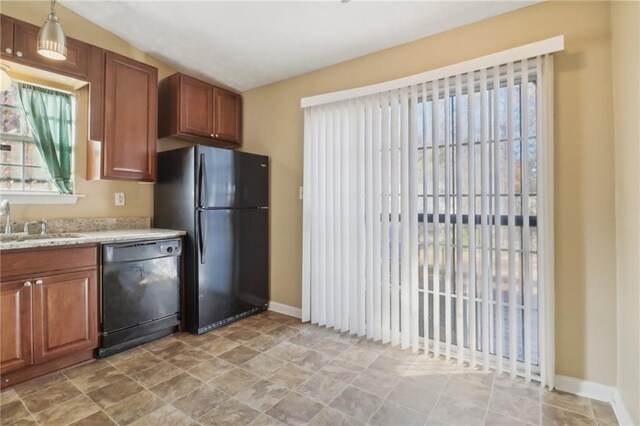 kitchen featuring black appliances, sink, vaulted ceiling, decorative light fixtures, and light stone counters