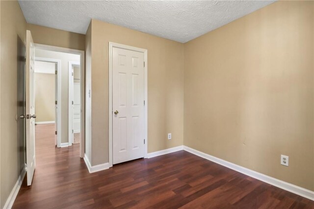 spare room featuring dark hardwood / wood-style flooring and a textured ceiling