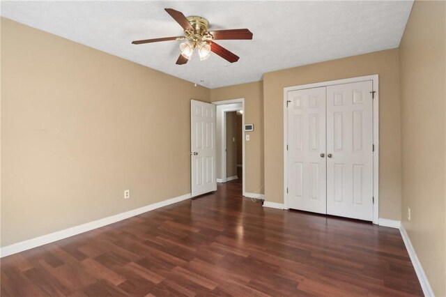 unfurnished bedroom with a closet, dark hardwood / wood-style floors, and ceiling fan