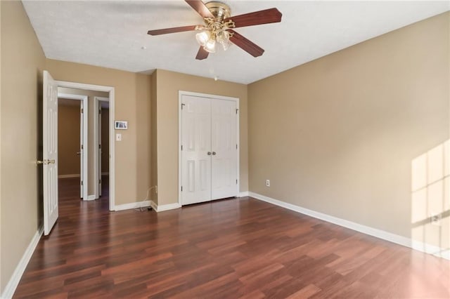 unfurnished bedroom with ceiling fan, dark hardwood / wood-style floors, and a closet