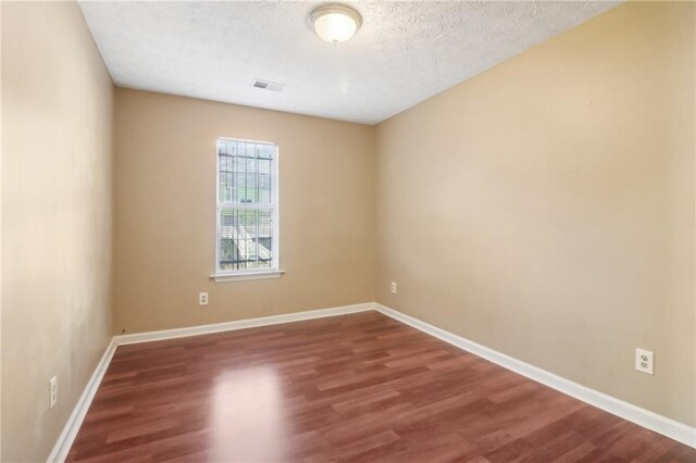 unfurnished room with dark hardwood / wood-style flooring and a textured ceiling