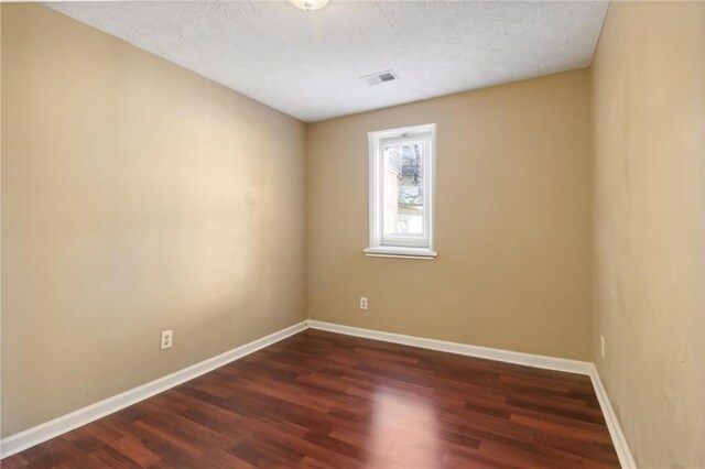 unfurnished room featuring a textured ceiling and dark wood-type flooring