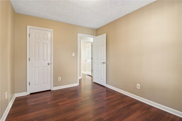 unfurnished bedroom featuring a textured ceiling and dark wood-type flooring