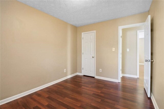 unfurnished bedroom with a textured ceiling and dark wood-type flooring