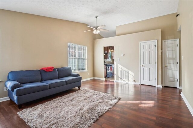 living room with a textured ceiling, ceiling fan, and dark wood-type flooring