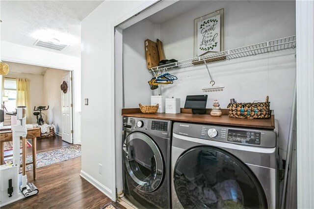 clothes washing area featuring dark hardwood / wood-style flooring, washer and clothes dryer, and a textured ceiling