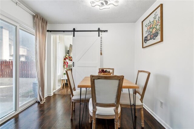 dining space featuring a textured ceiling, a barn door, a healthy amount of sunlight, and dark hardwood / wood-style floors