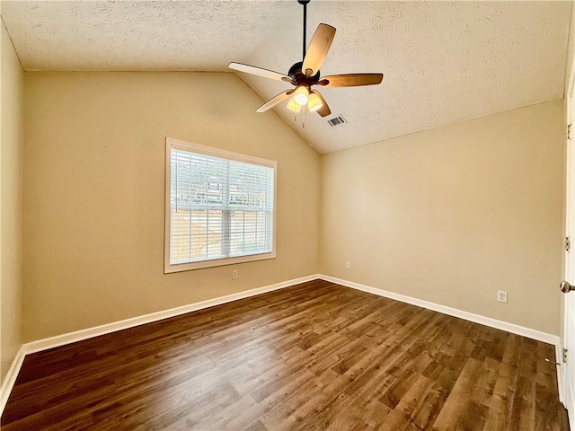 unfurnished room with vaulted ceiling, dark hardwood / wood-style floors, a textured ceiling, and ceiling fan