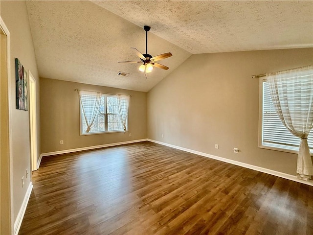 empty room featuring dark wood-type flooring, ceiling fan, lofted ceiling, and a textured ceiling