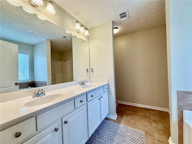 bathroom featuring vanity, tile patterned flooring, independent shower and bath, and a textured ceiling