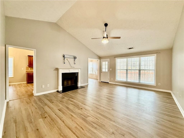 unfurnished living room with ceiling fan, high vaulted ceiling, light hardwood / wood-style floors, and a healthy amount of sunlight