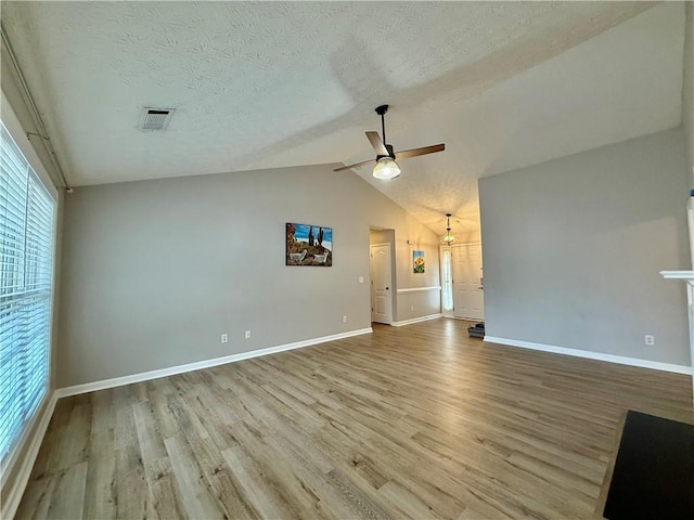 unfurnished living room featuring ceiling fan, lofted ceiling, a textured ceiling, and light wood-type flooring