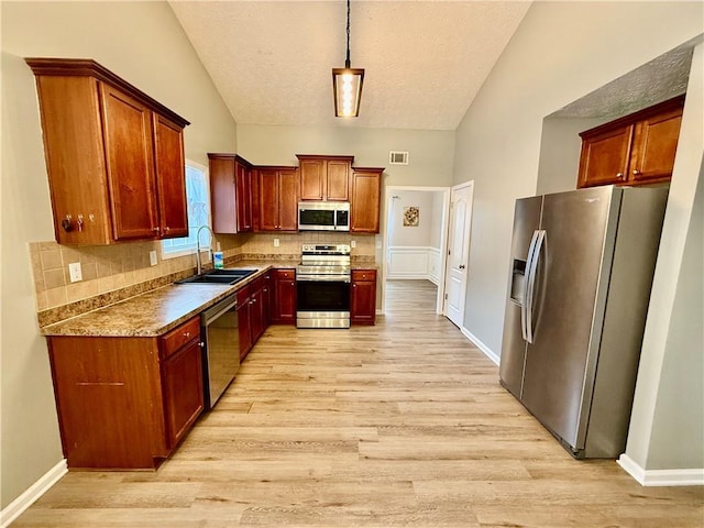 kitchen with lofted ceiling, sink, tasteful backsplash, appliances with stainless steel finishes, and light hardwood / wood-style floors