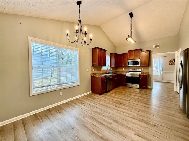 kitchen featuring appliances with stainless steel finishes, sink, hanging light fixtures, and light hardwood / wood-style flooring