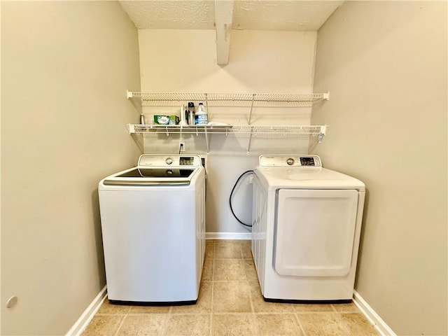 laundry area with separate washer and dryer, light tile patterned floors, and a textured ceiling