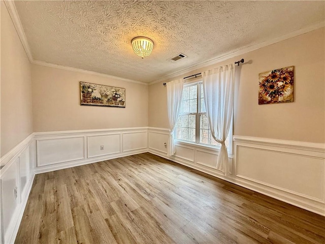 unfurnished room with crown molding, wood-type flooring, and a textured ceiling