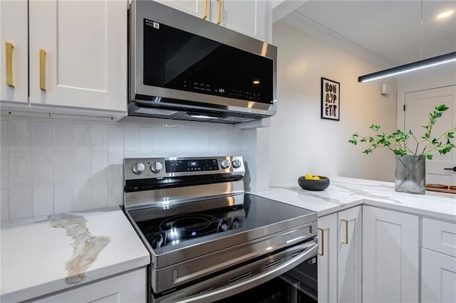 4282 Roswell Rd NE Unit G1, Atlanta, GA 30342 - kitchen with stainless steel appliances, white cabinetry, decorative backsplash, crown molding, and light stone counters