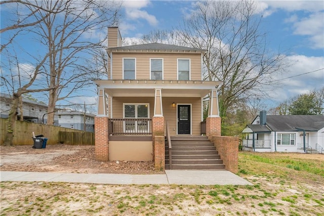 view of front of property featuring covered porch, brick siding, fence, stairway, and a chimney