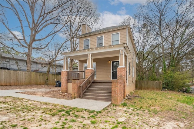 american foursquare style home featuring stairs, a porch, a chimney, and fence