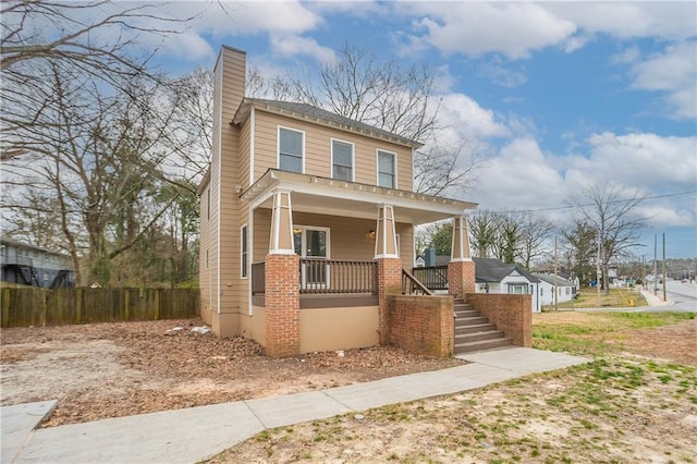 american foursquare style home featuring a porch, stairway, fence, and a chimney