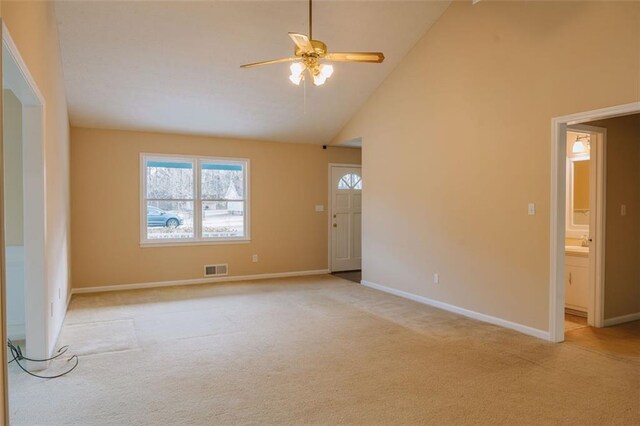 unfurnished living room featuring ceiling fan, a fireplace, high vaulted ceiling, and light carpet