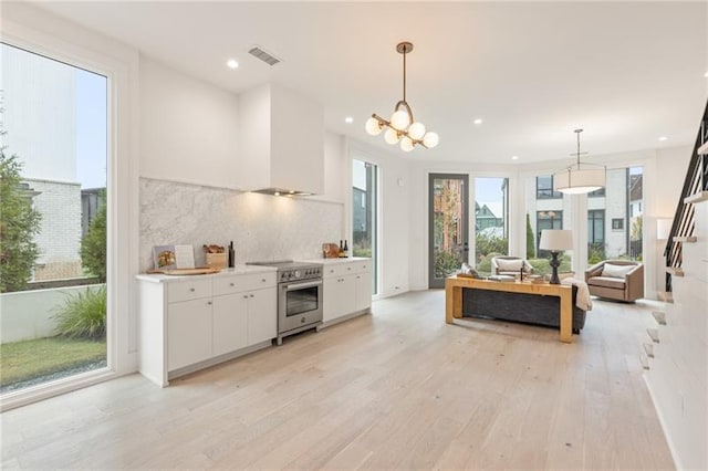 kitchen with tasteful backsplash, decorative light fixtures, light hardwood / wood-style floors, white cabinetry, and stainless steel electric range