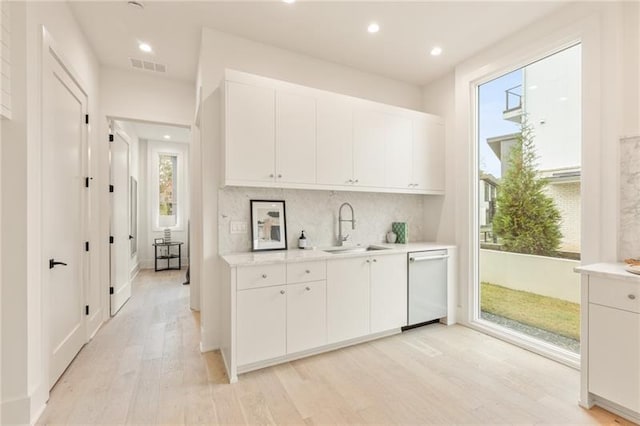 kitchen featuring white dishwasher, white cabinetry, light hardwood / wood-style floors, and sink