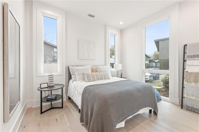 bedroom with light hardwood / wood-style floors and multiple windows