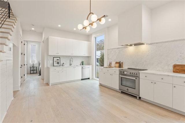 kitchen with decorative light fixtures, white cabinetry, decorative backsplash, and high end stove