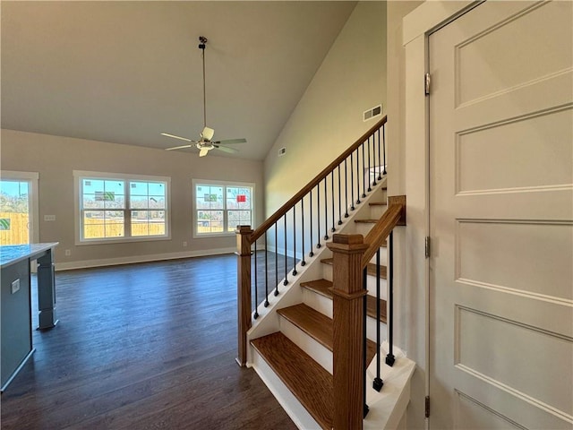 stairway featuring baseboards, visible vents, ceiling fan, wood finished floors, and high vaulted ceiling