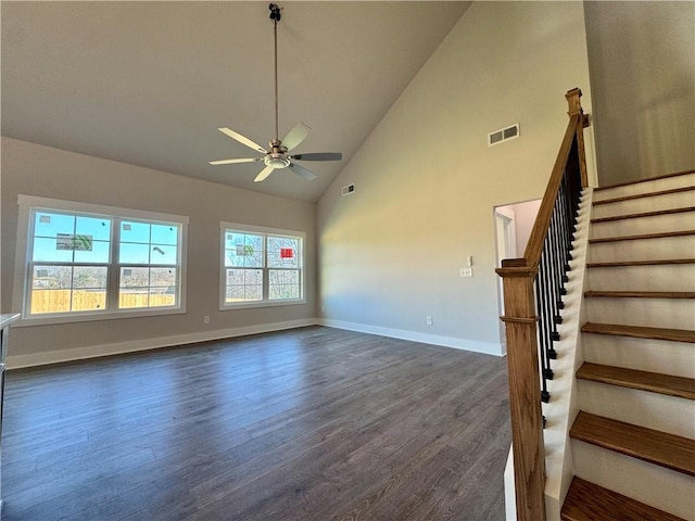 unfurnished living room featuring baseboards, visible vents, dark wood-style floors, stairway, and high vaulted ceiling