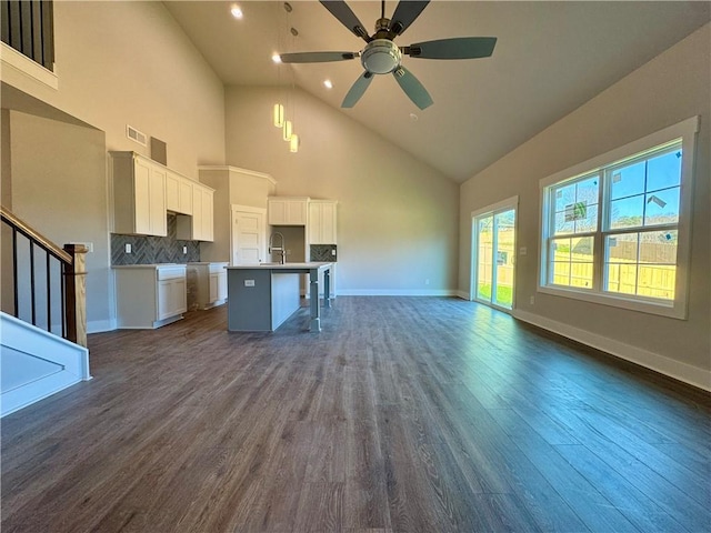 kitchen with open floor plan, a sink, a kitchen island with sink, and dark wood-style floors