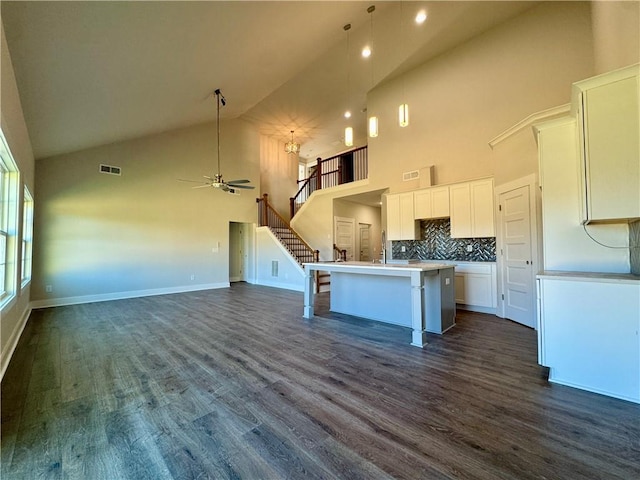 kitchen with a breakfast bar, visible vents, white cabinetry, open floor plan, and an island with sink