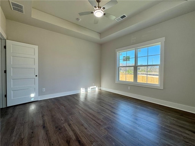 empty room featuring baseboards, visible vents, and a raised ceiling