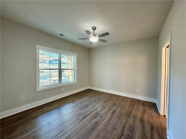 spare room with dark wood-style floors, visible vents, baseboards, and a ceiling fan